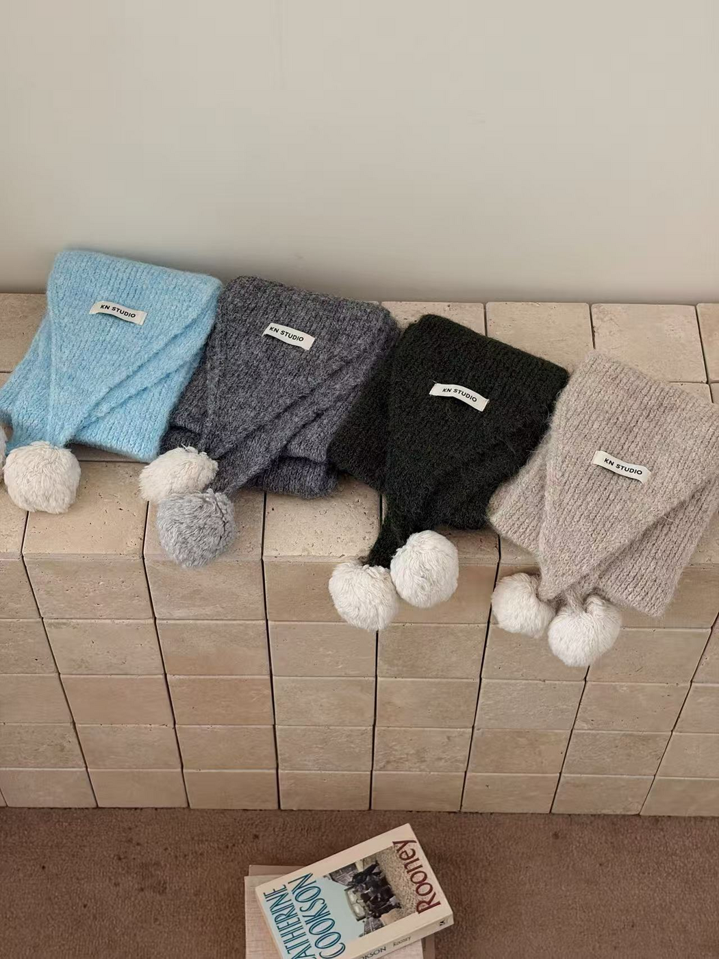 Blue, Gray, Green and Beige scarves arranged side by side with tapered ends and pom-poms