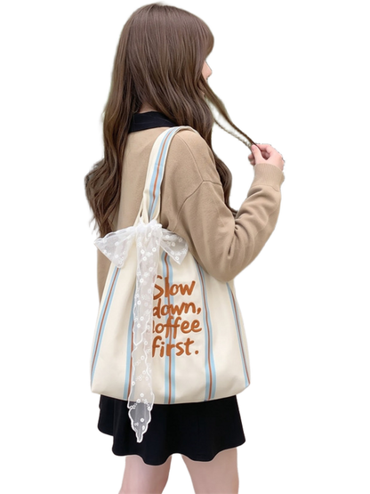 Blue striped tote bag displayed over a shoulder outdoors, rear three-quarter view