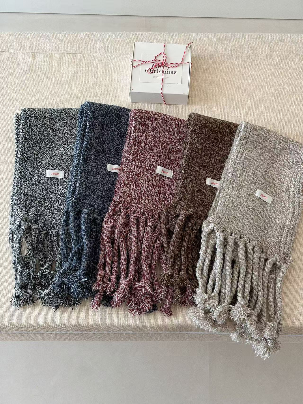Black, Navy, Burgundy, Brown and Gray marled knit scarves arranged side by side with fringe extended