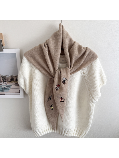 Beige embroidered knit scarf looped over a hanging white top