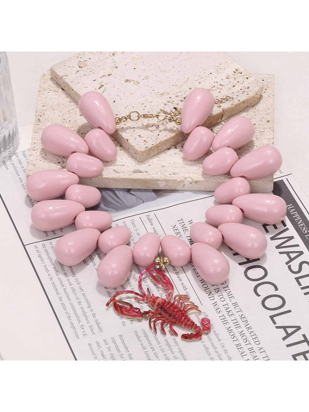 Close-up of Neckit statement bead necklace featuring lobster pendant on white background