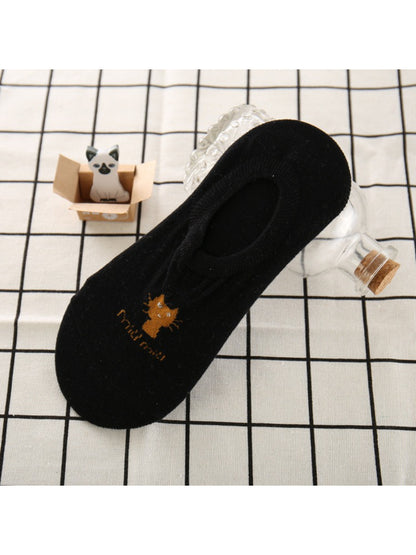 Top view of white no show socks with cat face on a wooden surface