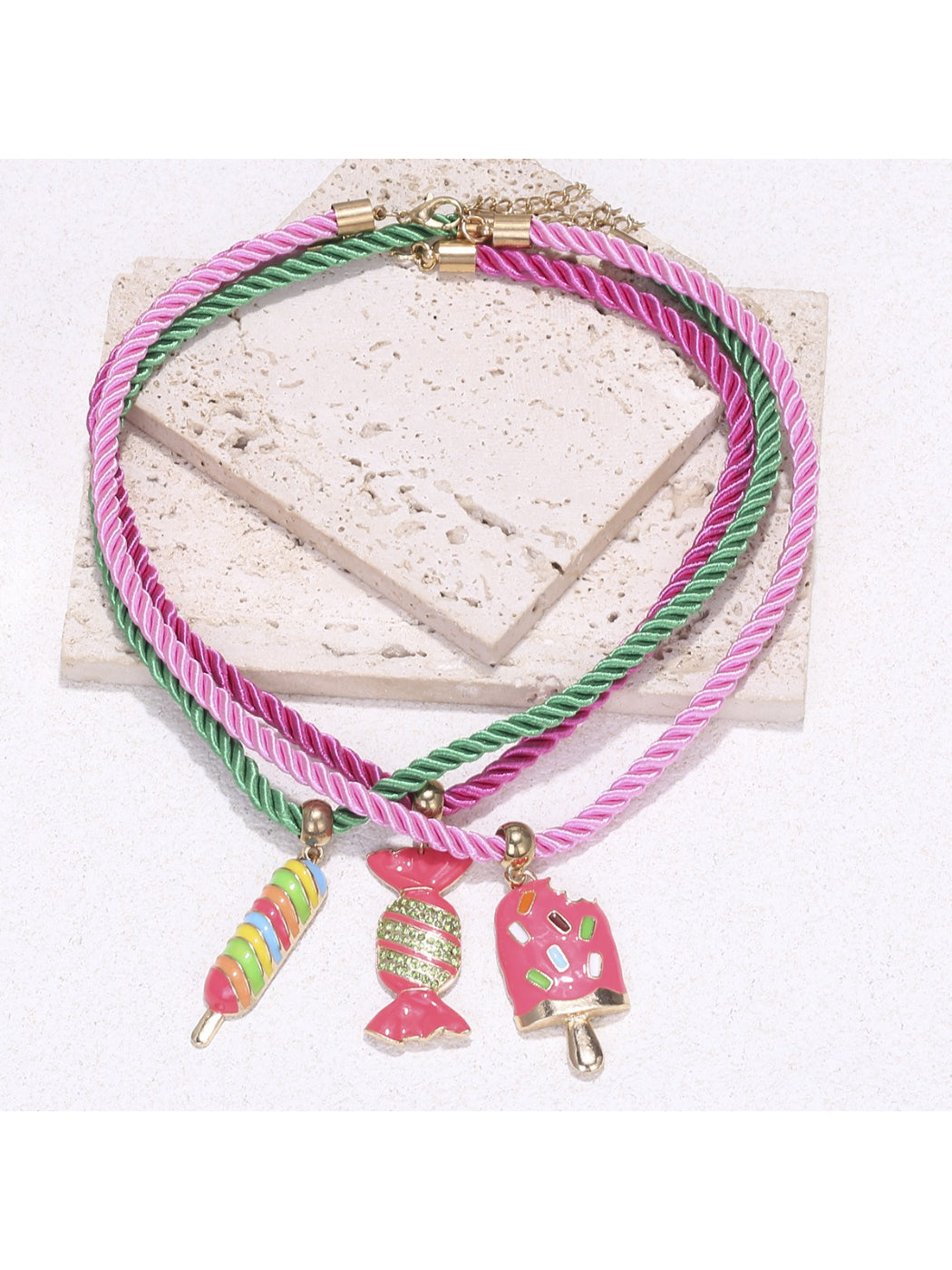 Neckit color rope necklace with candy charms arranged in a circular shape on a plain surface