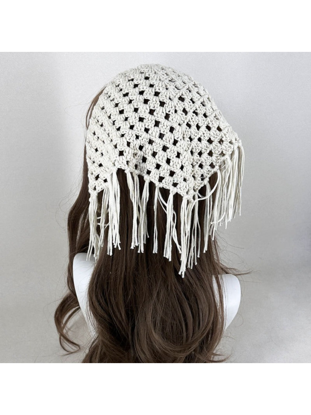 Boho tassel crochet bandana in cream color styled on a wooden surface