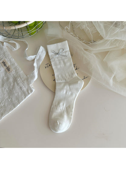 Rufia socks worn on feet highlighting bow and knit texture