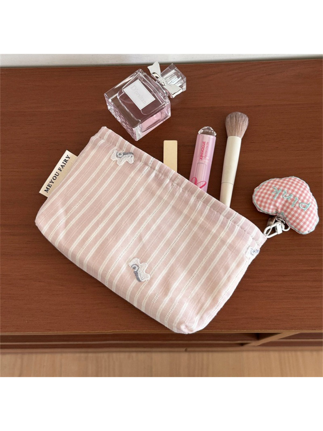 Cosbai gingham pink makeup pouch next to cosmetic brushes and lipstick