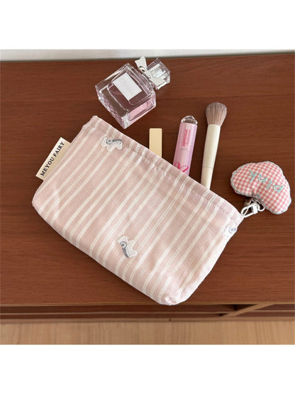 Cosbai gingham pink makeup pouch next to cosmetic brushes and lipstick