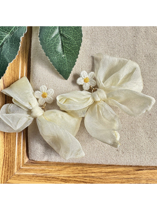 Close-up of Earwish soft ribbon daisy earrings with white petals and yellow centers