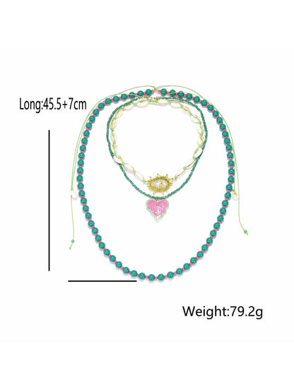Neckit layered beaded necklace with leaf pendant photographed on a dark textured background