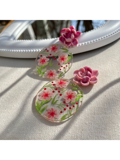Pair of Earwish Garden Flower Disc Earrings placed on a wooden surface with soft lighting