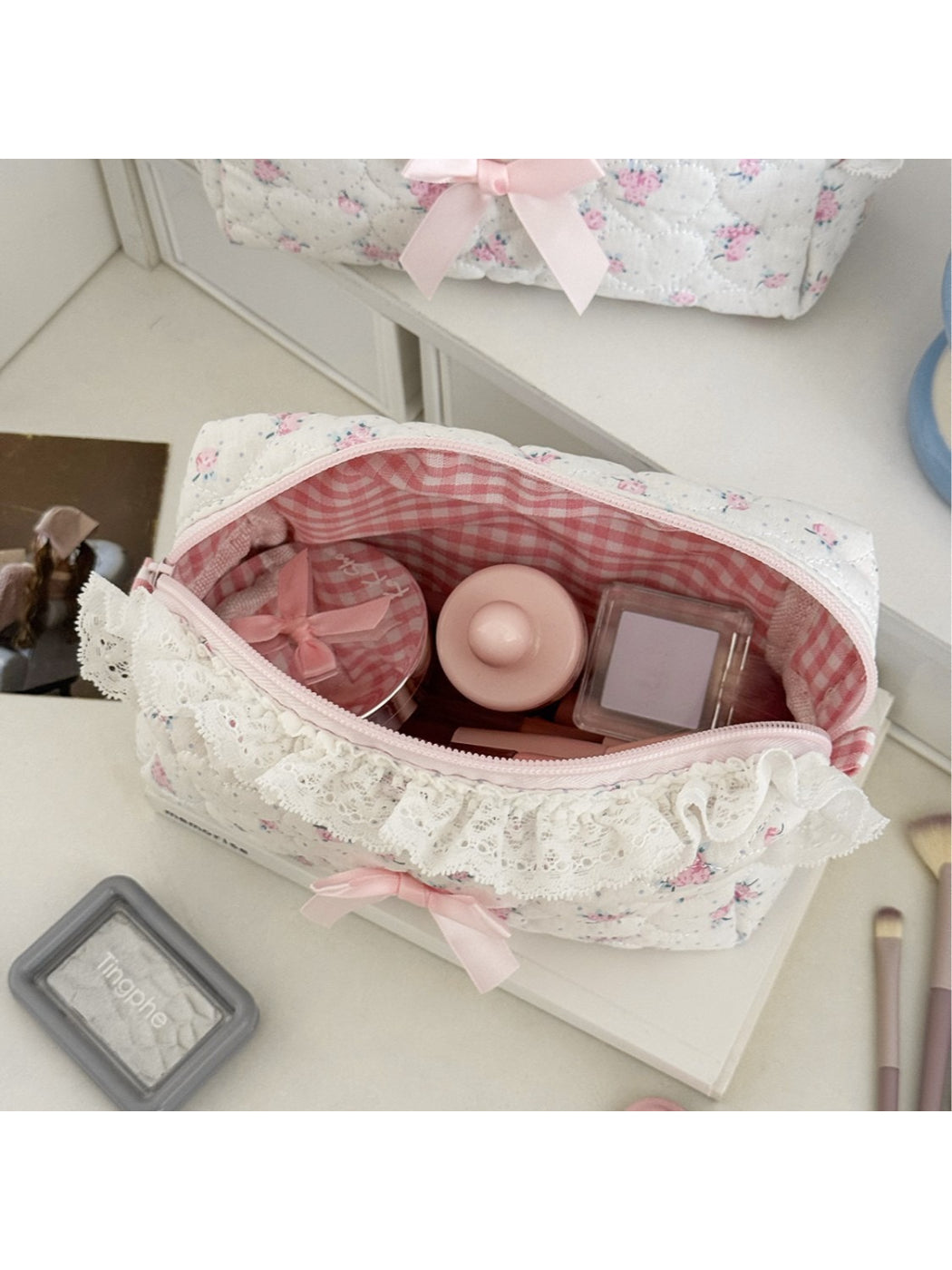 Cosbai makeup bag with various cosmetics inside on a white surface