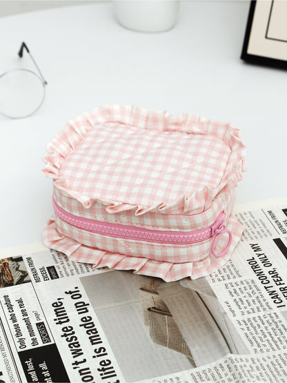 Three Cosbai checkered makeup pouches with ruffle trim arranged side by side