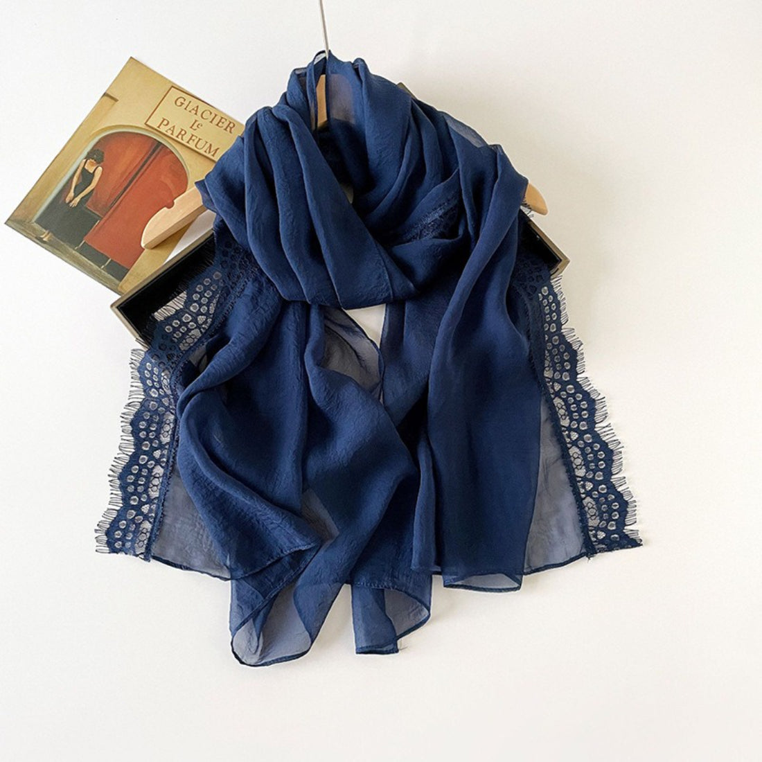 Folded lightweight scarf showing lace border design on soft fabric