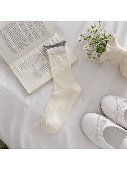 Rufia ribbed socks worn by model standing on wooden floor