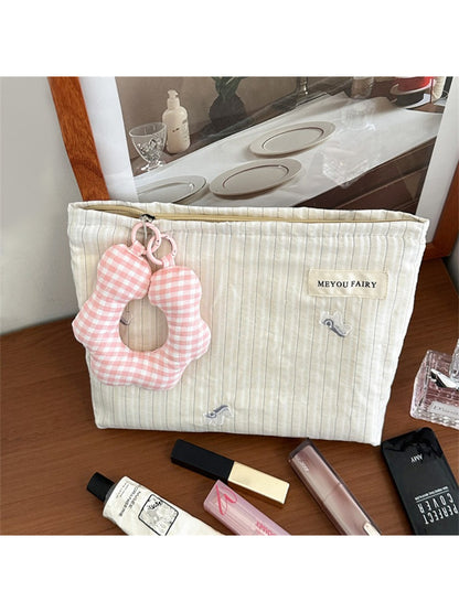 Striped cosmetic bag standing upright showing front design and charm