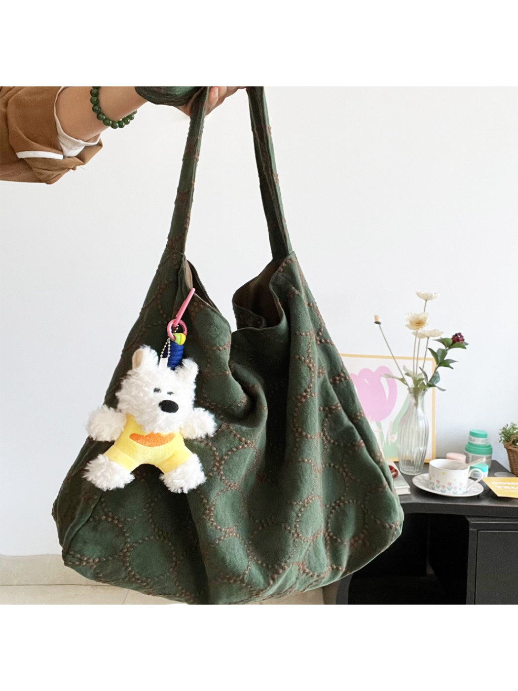 Close-up of beige Cosbai tote bag showing textured material and dog charm detail