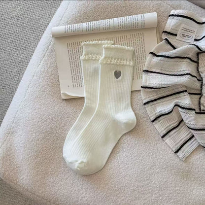 Side view of Rufia crew socks highlighting embroidered heart on ankle area