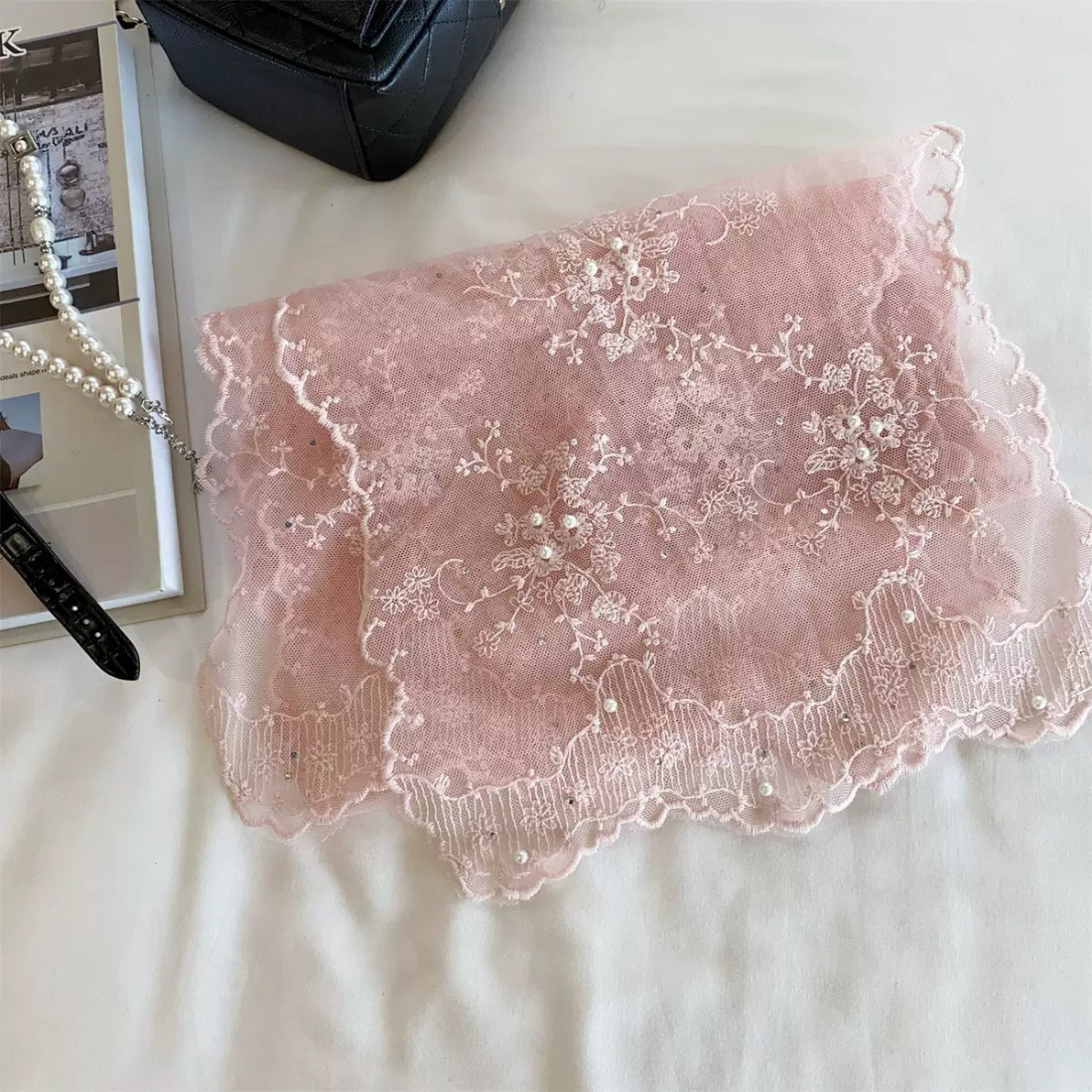 Sheer mesh scarf with botanical design folded on a wooden surface