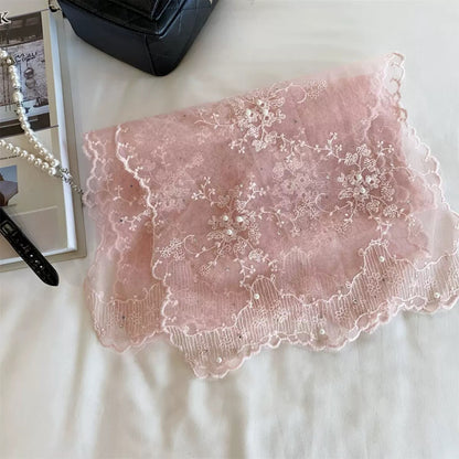 Sheer mesh scarf with botanical design folded on a wooden surface