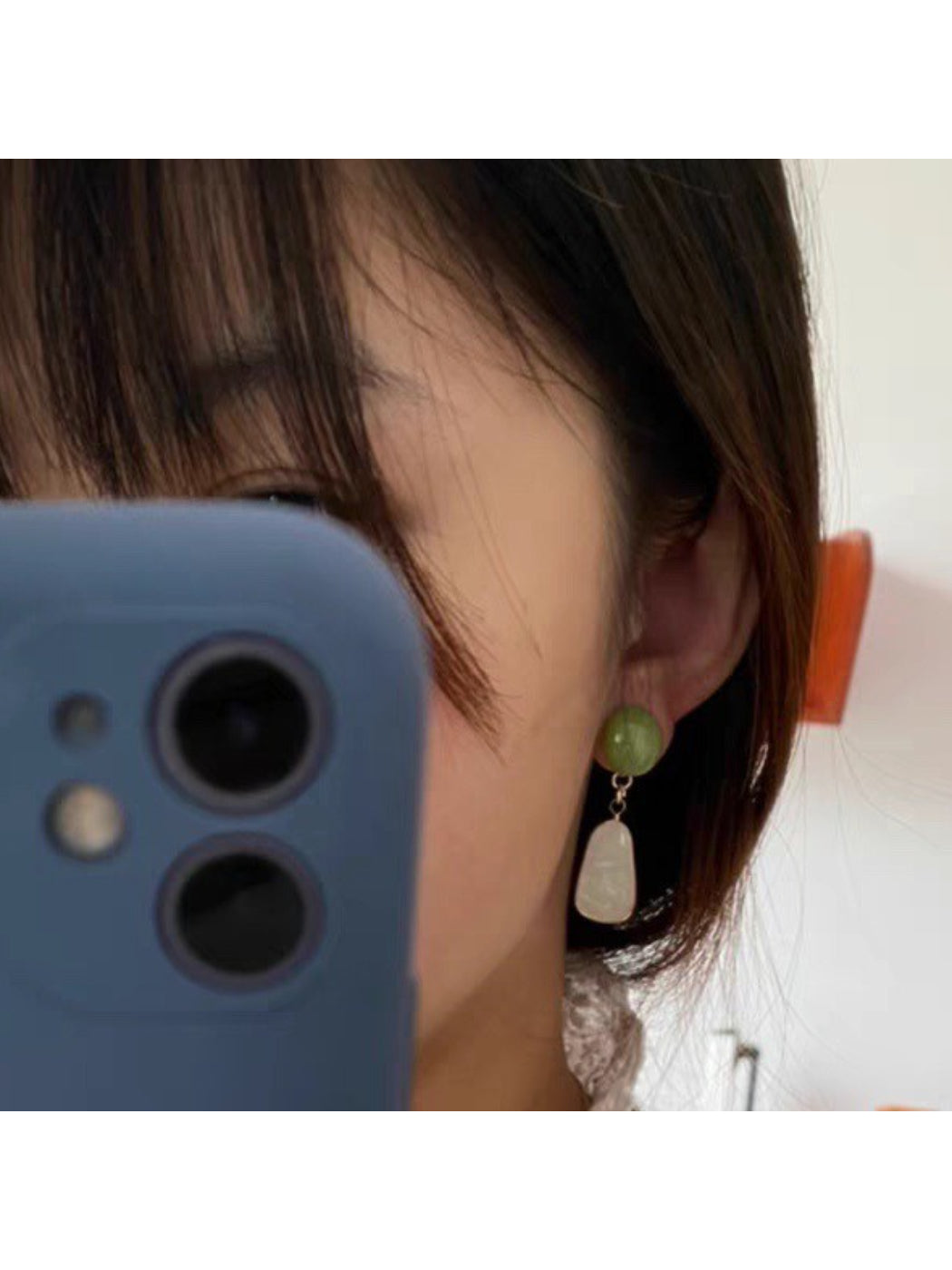 Close-up of green oval stone in Earwish earrings with gold detailing