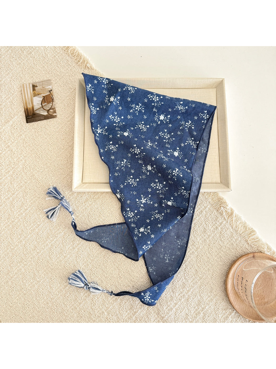 Blue triangle scarf with floral pattern and tassel edges laid flat