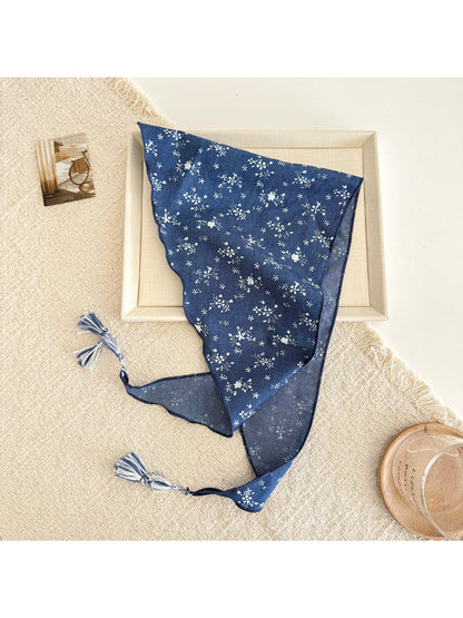 Blue triangle scarf with floral pattern and tassel edges laid flat