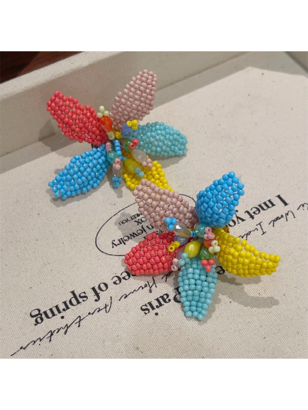 Close-up of colorful beaded flower earrings with pink, yellow, and green beads