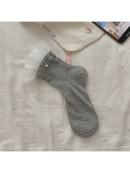 Rufia sheer crew socks with ruffle trim displayed on wooden surface
