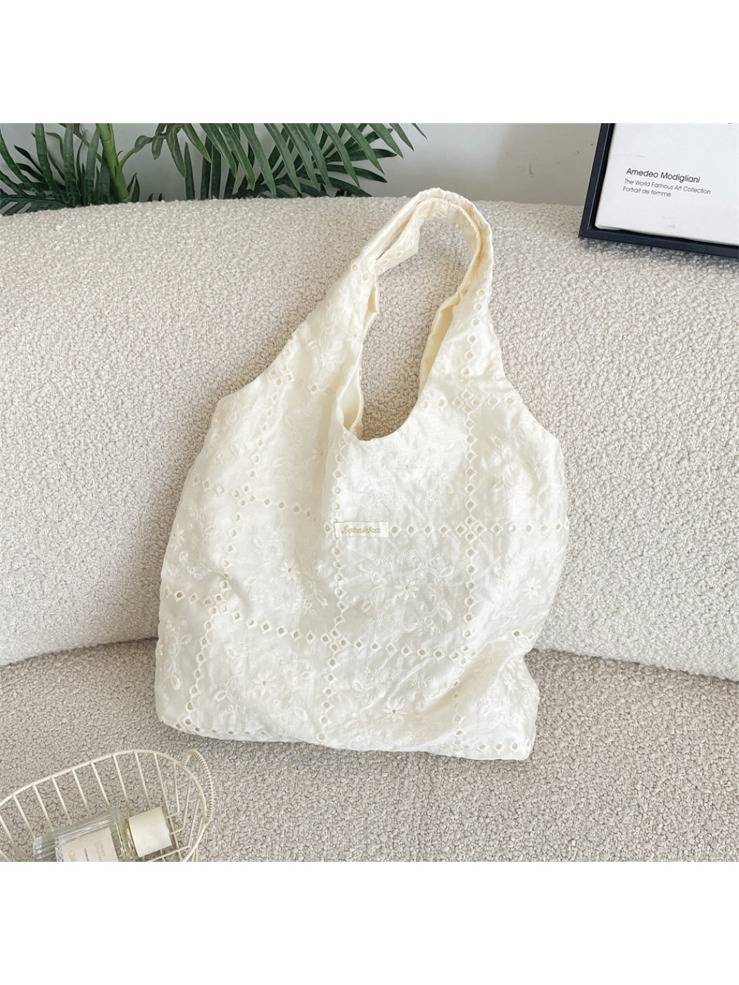 White hobo bag with intricate floral embroidery and adjustable shoulder strap