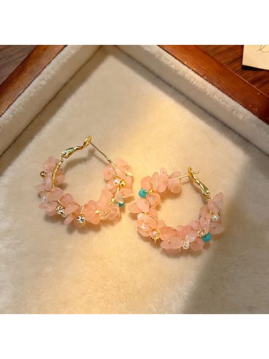 Close-up of Earwish light tone floral hoop earrings on white background