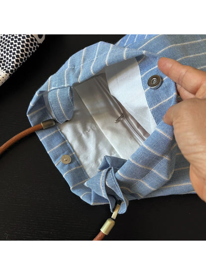 Cosbai blue stripe slouch shoulder bag displayed on a wooden surface with lighting