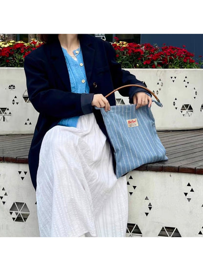 Cosbai blue stripe slouch shoulder bag worn over a shoulder by a model in casual outfit