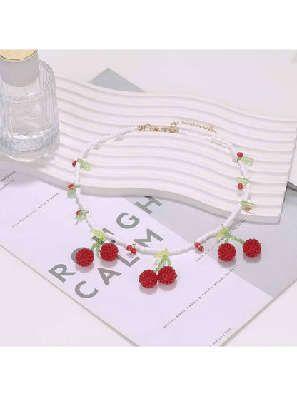 Close-up of Neckit cherry pendant necklace featuring red cherry and white beads