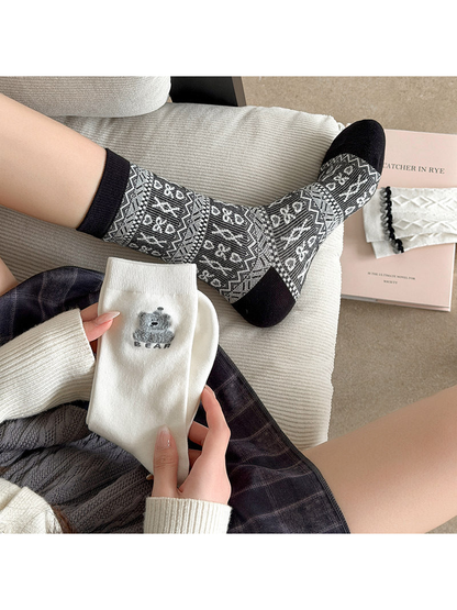 Patterned sock worn while a white bear sock is held in a relaxed seating scene