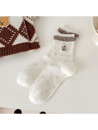 Ivory ribbed bear-motif socks with small contrasting dots and brown braided cuff trim.