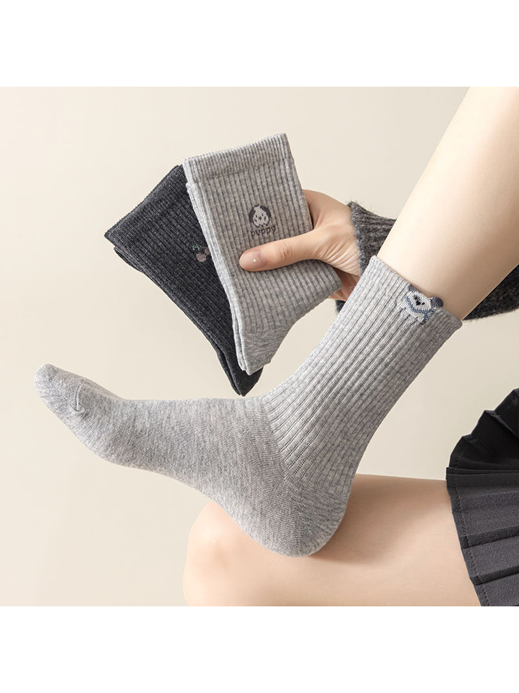 Gray dog-motif sock worn while other socks are held nearby