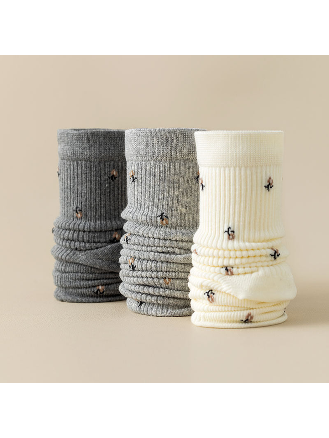 Dark gray, gray, and ivory ribbed crew socks with multicolor motifs displayed together