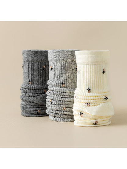 Dark gray, gray, and ivory ribbed crew socks with multicolor motifs displayed together