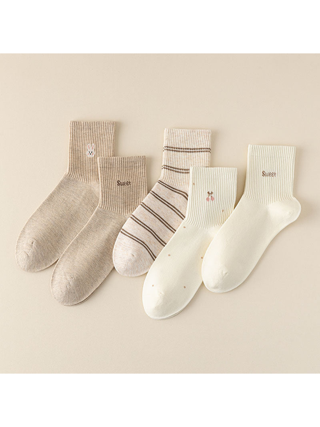 Five neutral crew socks with lettering, rabbit, cherry, and stripe motifs