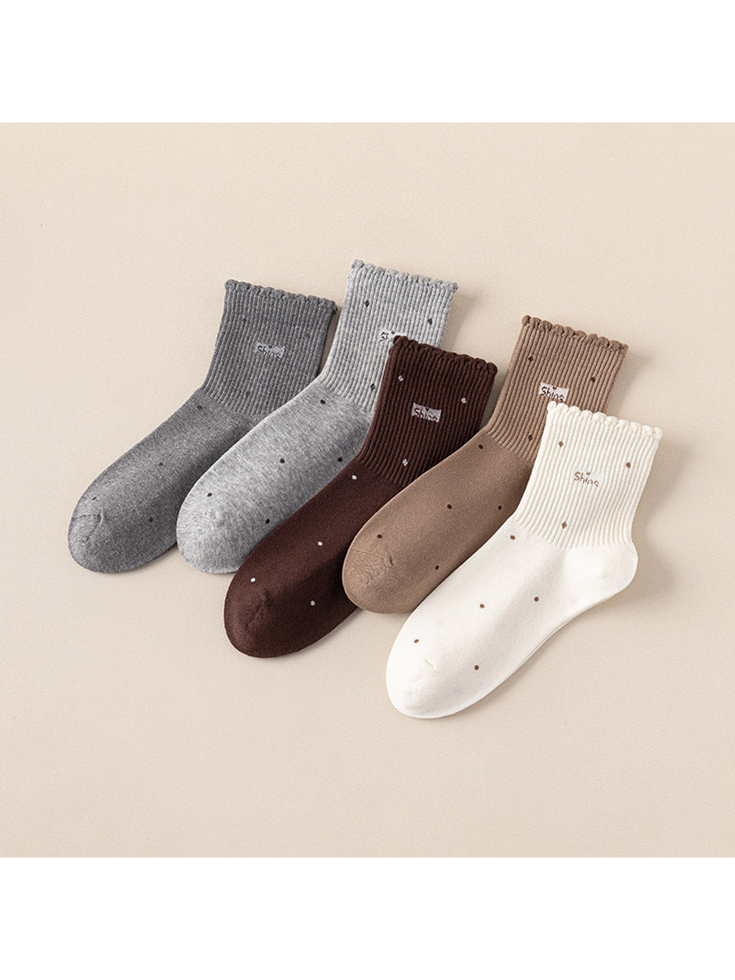 Five neutral-color crew socks displayed together with scattered dot motifs and scalloped cuffs