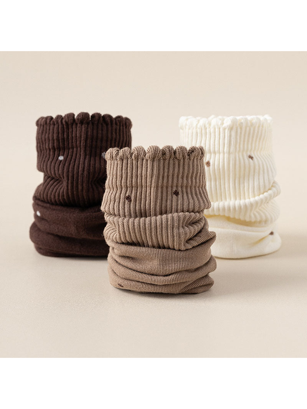 Brown, khaki, and white crew socks stacked in folded rolls