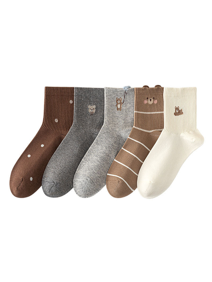 Five crew sock styles displayed together, featuring polka dots, bear motifs, a balloon detail and stripes