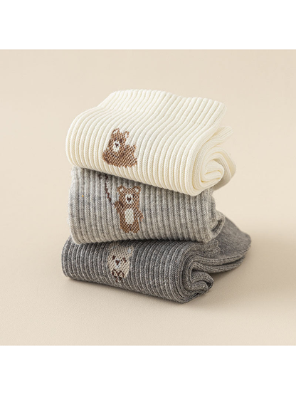 Folded ivory, light gray and dark gray socks stacked to show ribbed cuffs and bear motifs