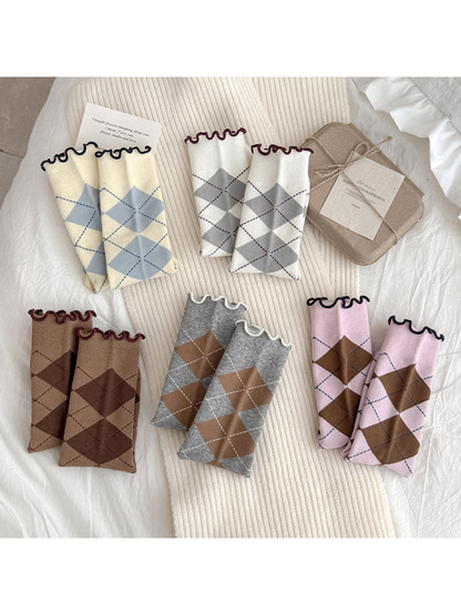 Five colors of argyle socks folded to display their diamond patterns and wavy cuffs