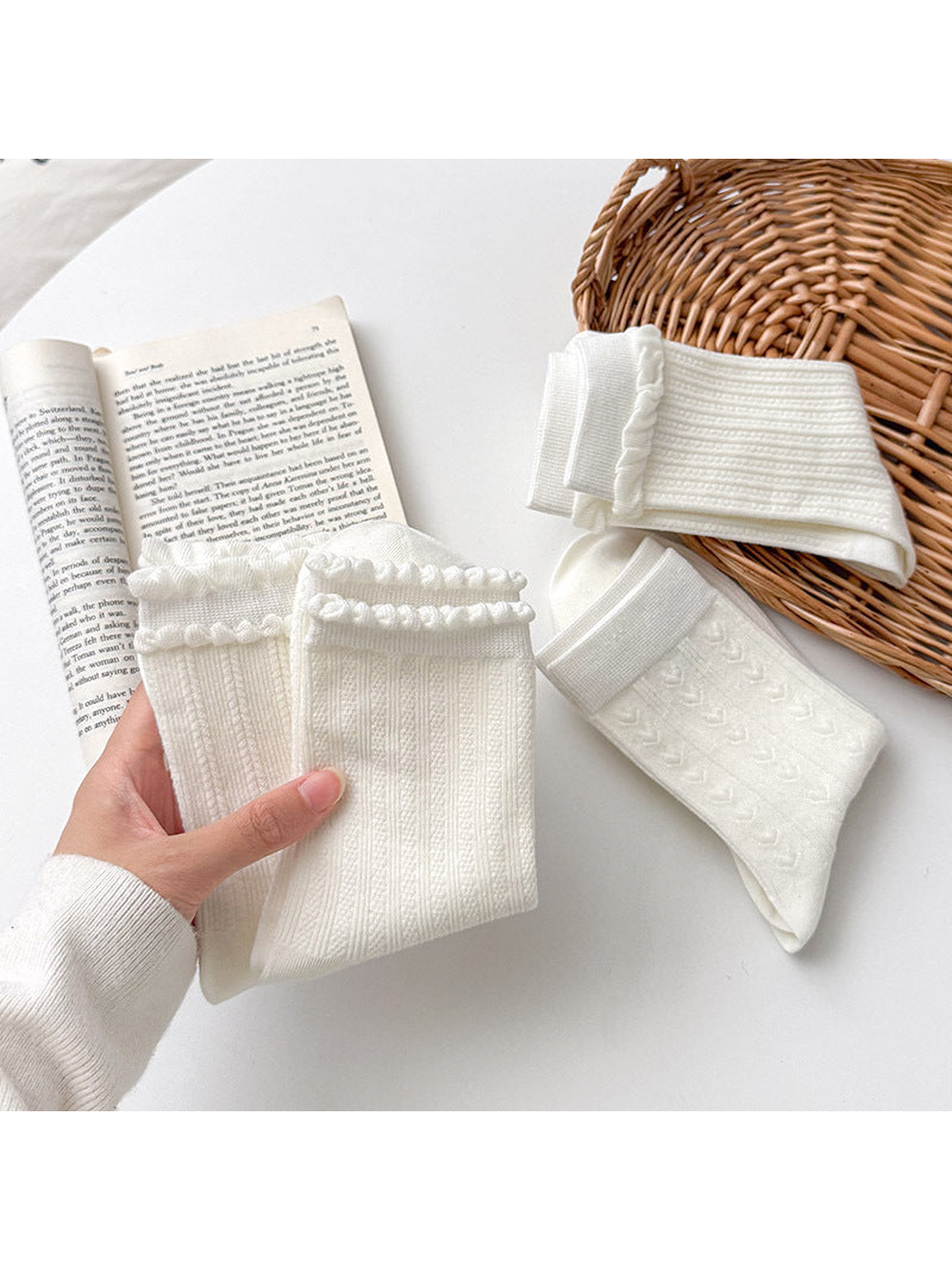 Close-up of white socks held to show ruffled cuffs and ribbed textures, with heart-pattern socks nearby.