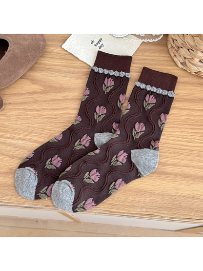 Burgundy crew socks with mauve tulip motifs, raised wavy lines, and gray heel and toe panels.