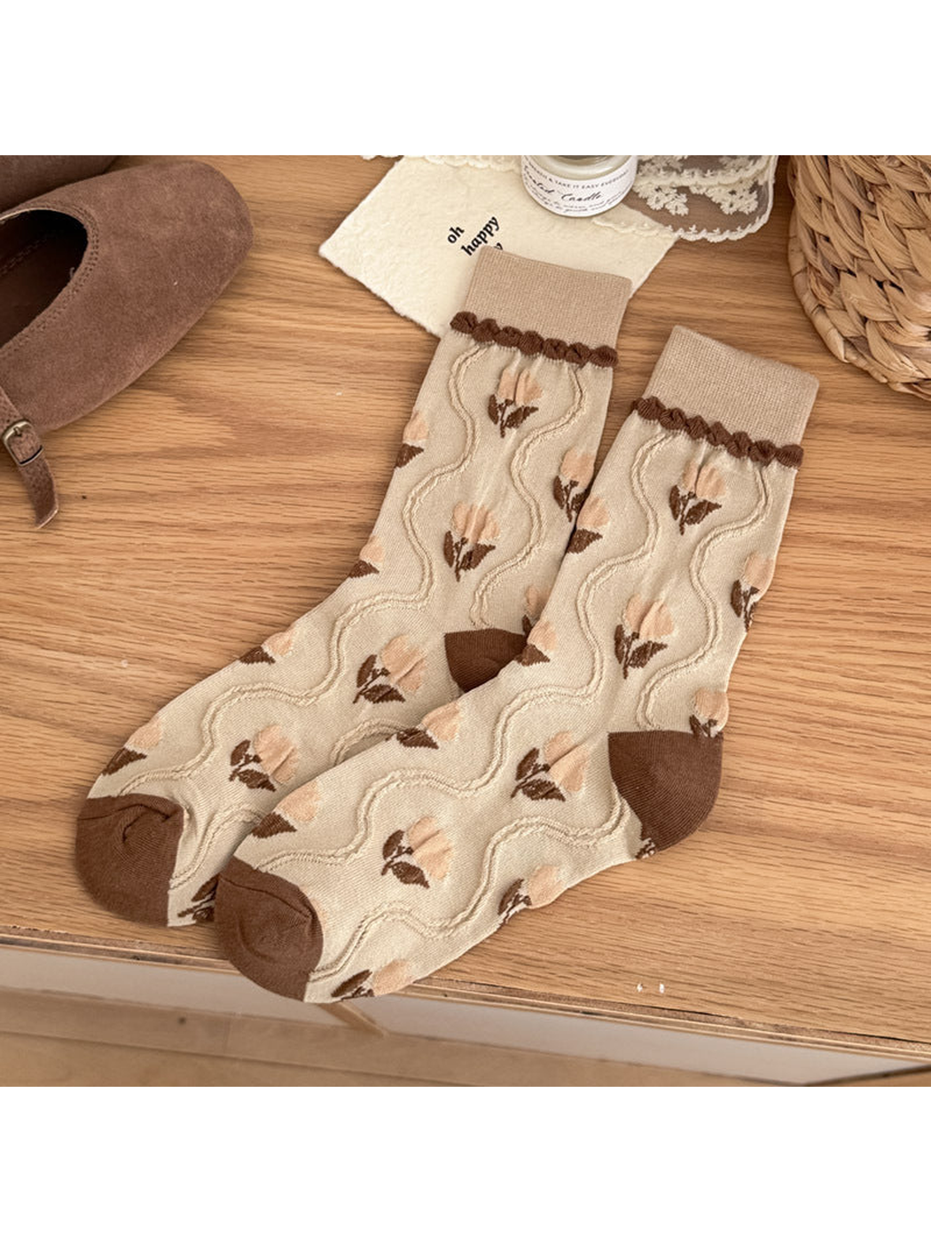 Beige crew socks with pale peach tulip motifs, raised wavy lines, and brown heel and toe panels.