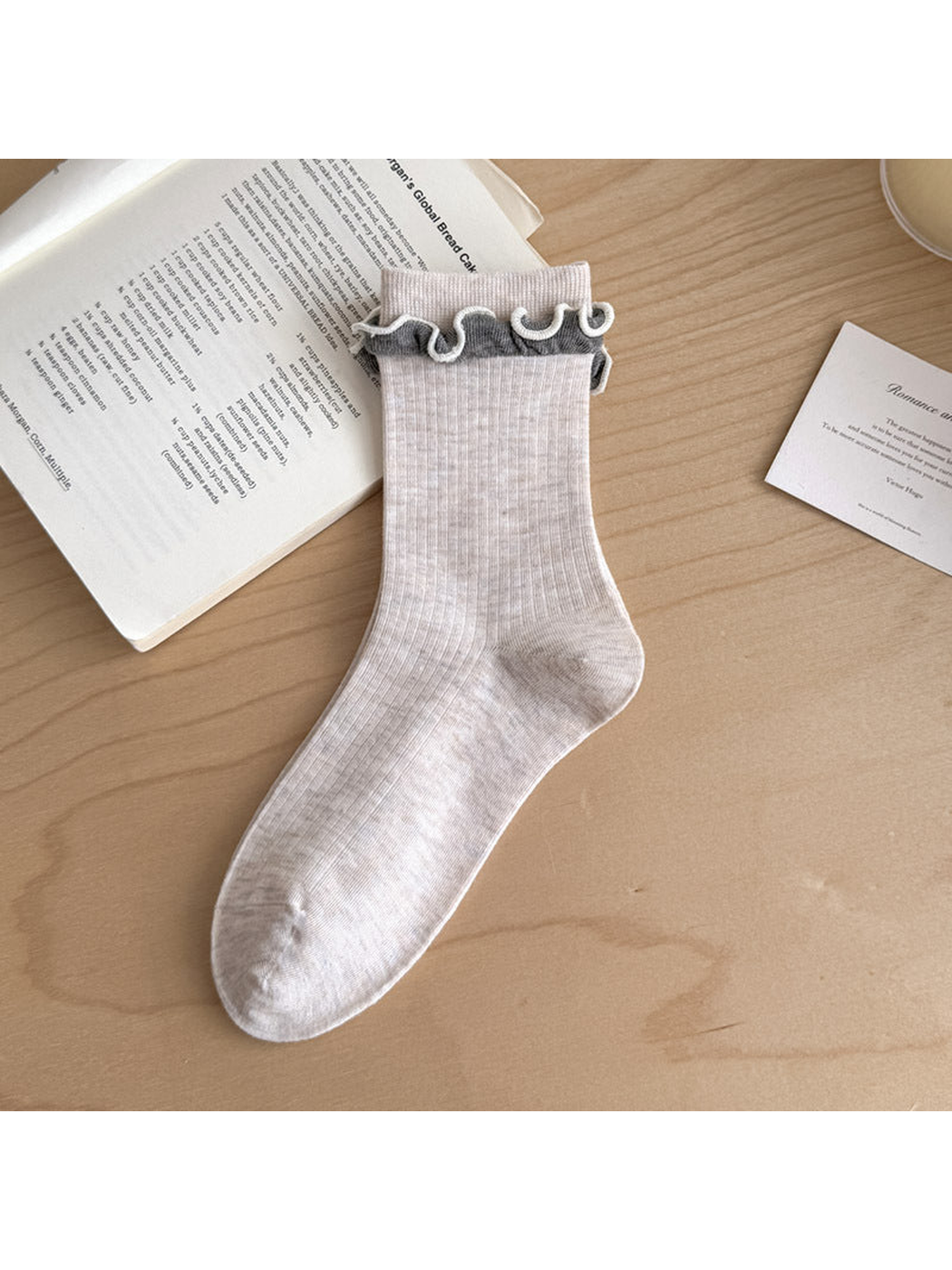 Ivory ribbed sock with contrasting gray ruffled trim below the cuff.