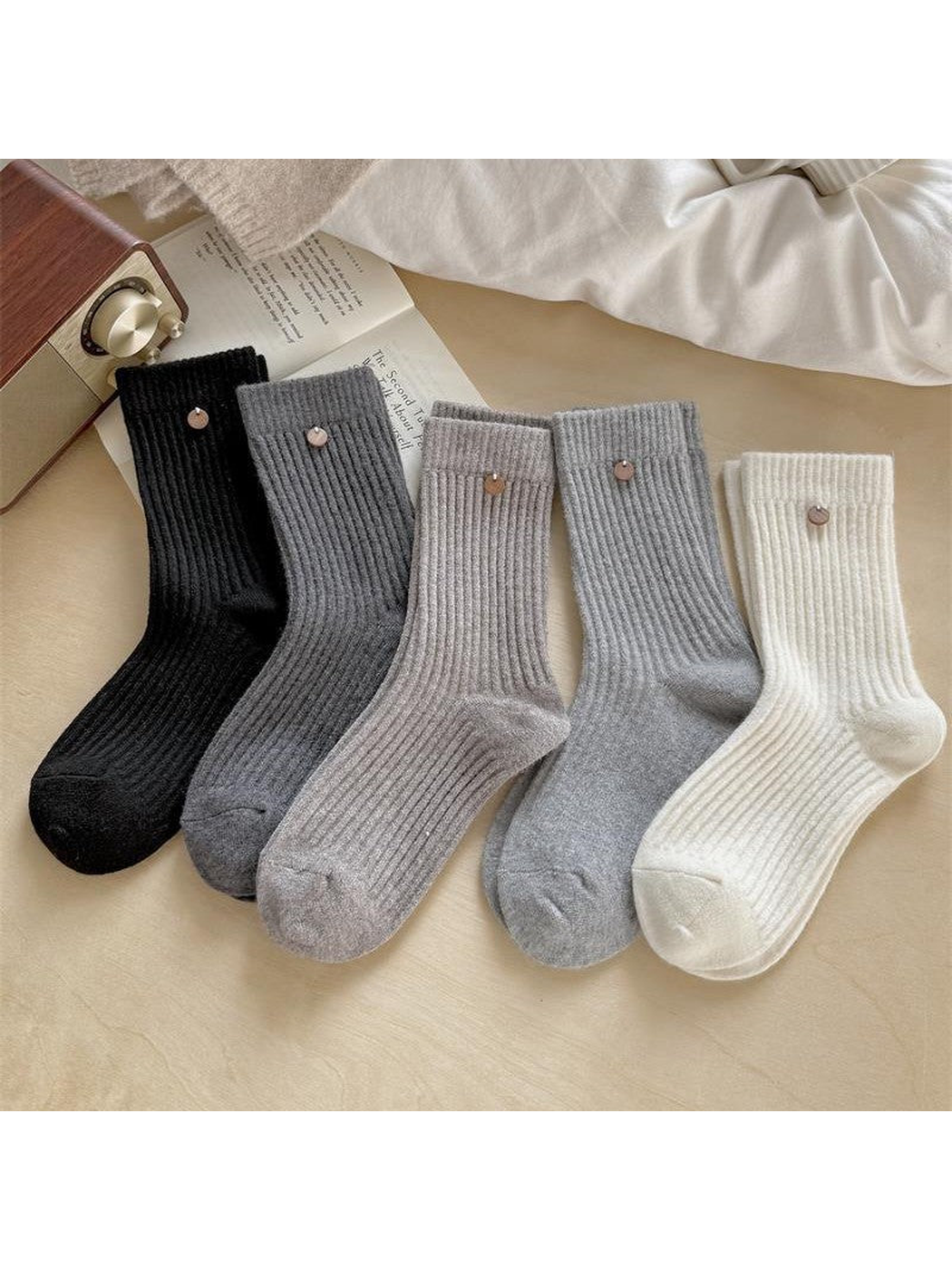 Ribbed socks in Black, Dark Gray, Greige, Gray and Ivory with small round ornaments below the cuffs.
