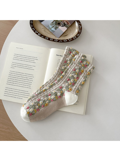 Beige floral socks with textured vertical bands and white toe and heel panels.